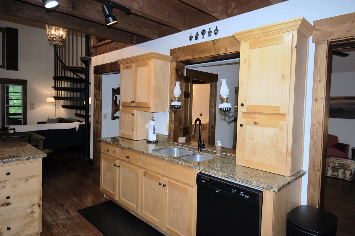 A close-up of the kitchen area with granite countertops, wooden cabinetry, a modern sink with a stylish faucet, and decorative lanterns. The layout suggests a fully equipped kitchen, perfect for culinary creativity and group meal prep.