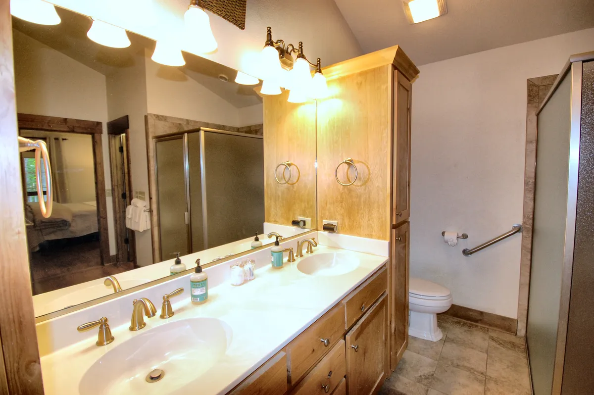 A modern, spa-like en-suite bathroom with a spacious double vanity, two mirrored cabinets, a glass-enclosed shower, and refreshing morning light. Ample countertop and storage space provide both function and luxury, enhancing the sense of a personal sanctuary.