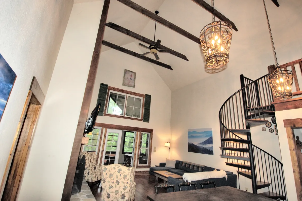This image showcases a spacious, inviting living area filled with natural light from large windows. A comfortable seating area is arranged around a central spot, perfect for gathering and storytelling. The ornate spiral staircase adds a sense of fun and adventure, while the decorative lighting enhances the cozy mood.